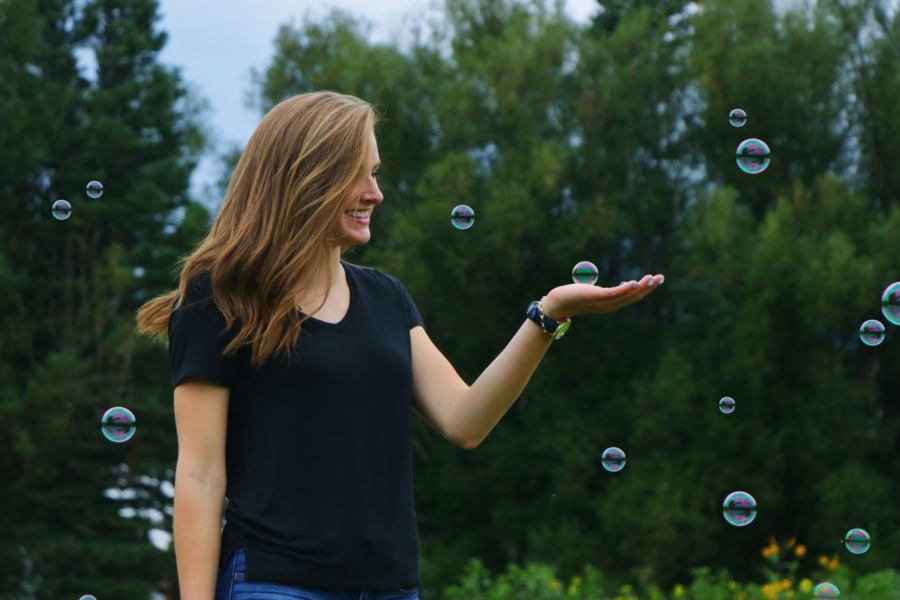 Woman joyfully catching a soap bubble on her hand.