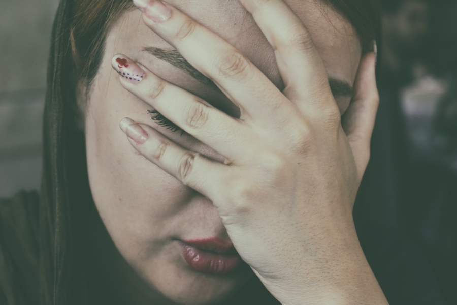 Woman with a migraine holding her head and wishing for relief.