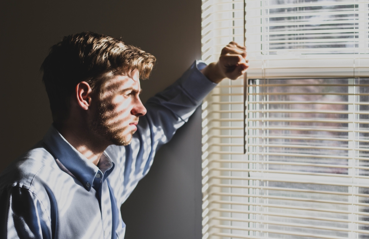 Depressed man looking out a window.