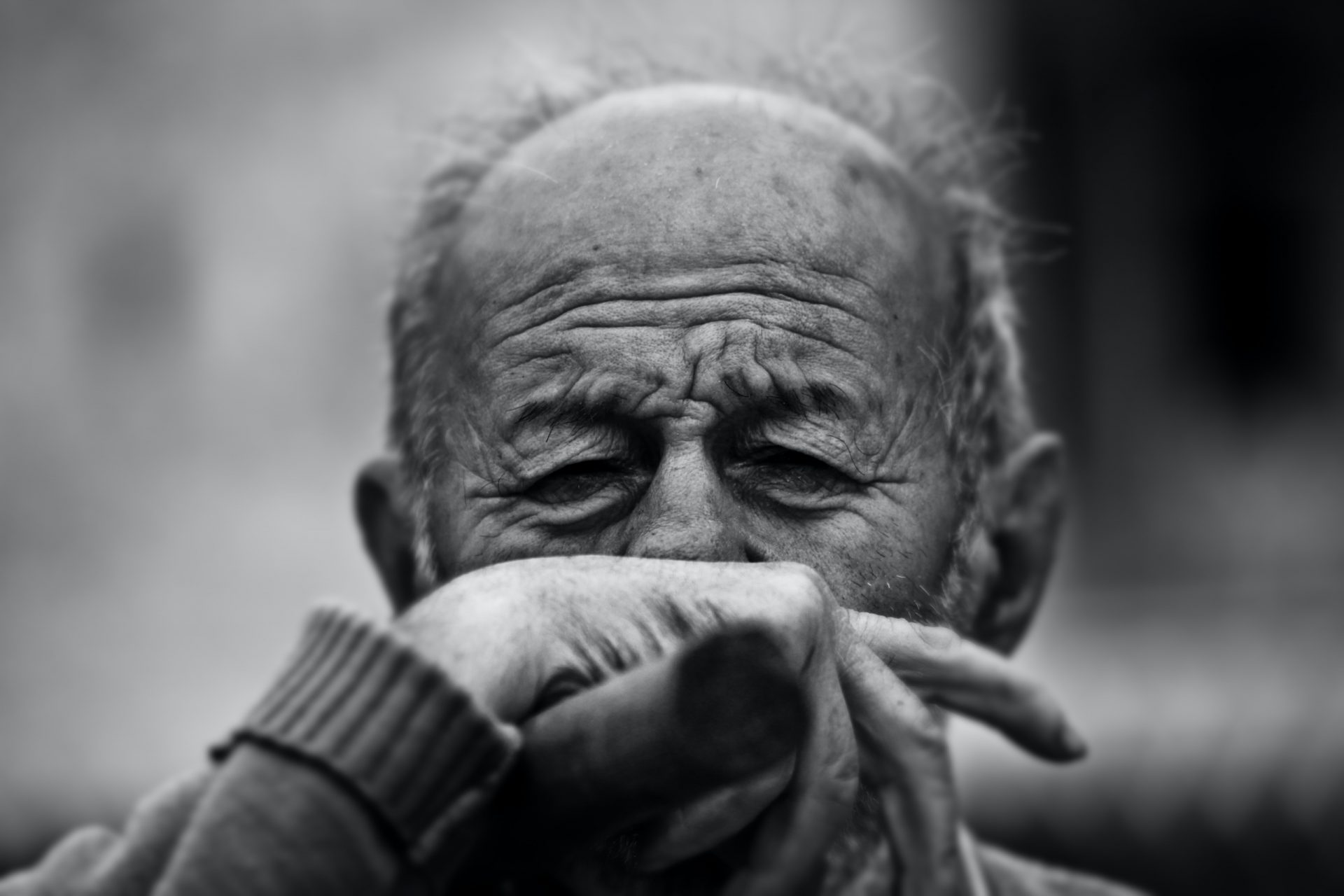 Elderly man with his hand covering his mouth in obvious discomfort.