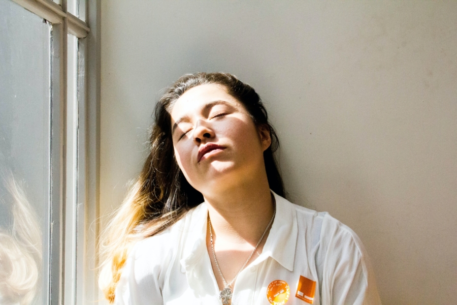 Woman leaning against a wall with her eyes closed because she suffers with insomnia.