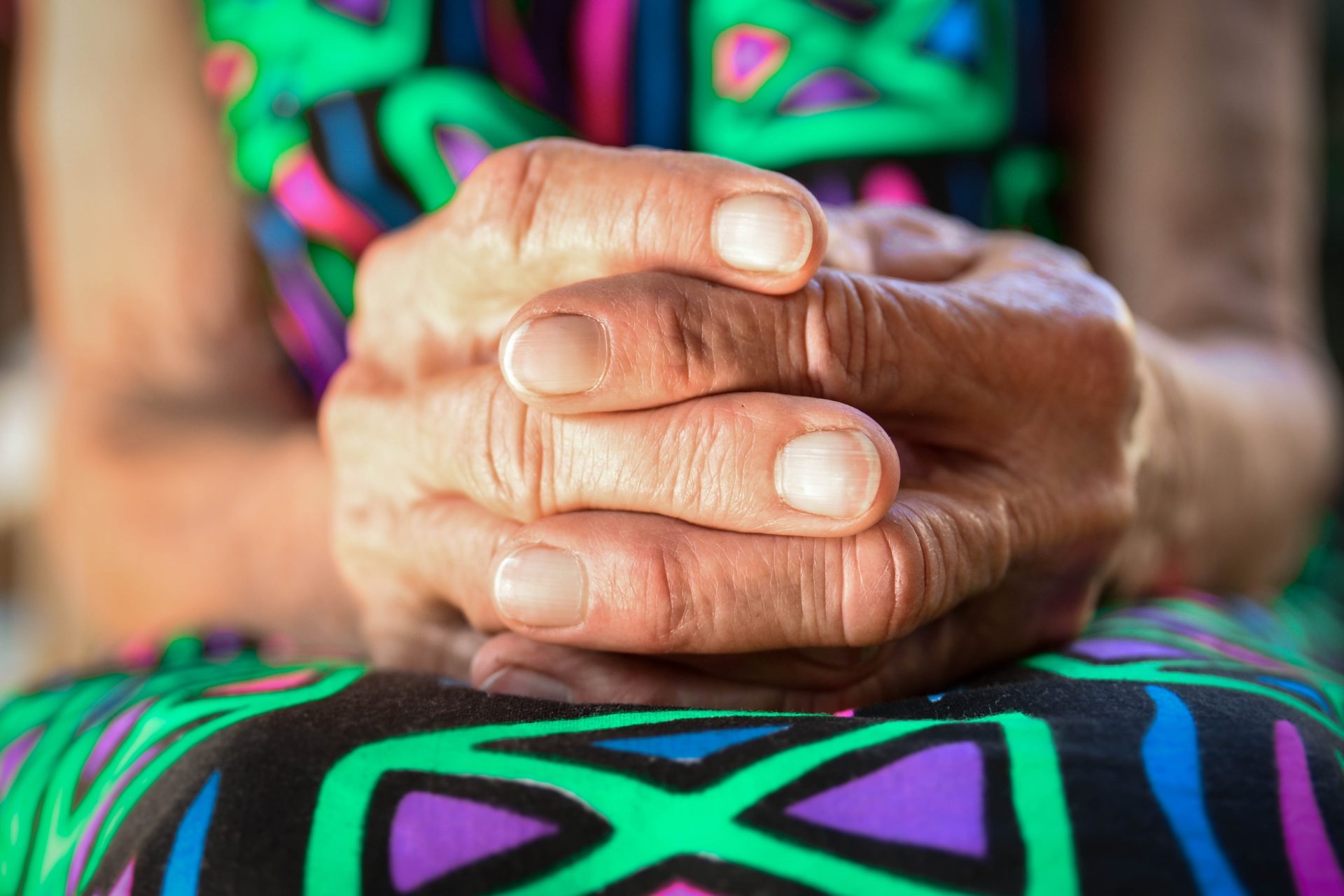 Woman with her arthritic hands in her lap.