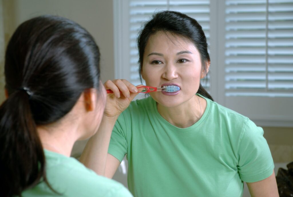 Woman looking in a mirror as she brushes her teeth with O'pa soap.