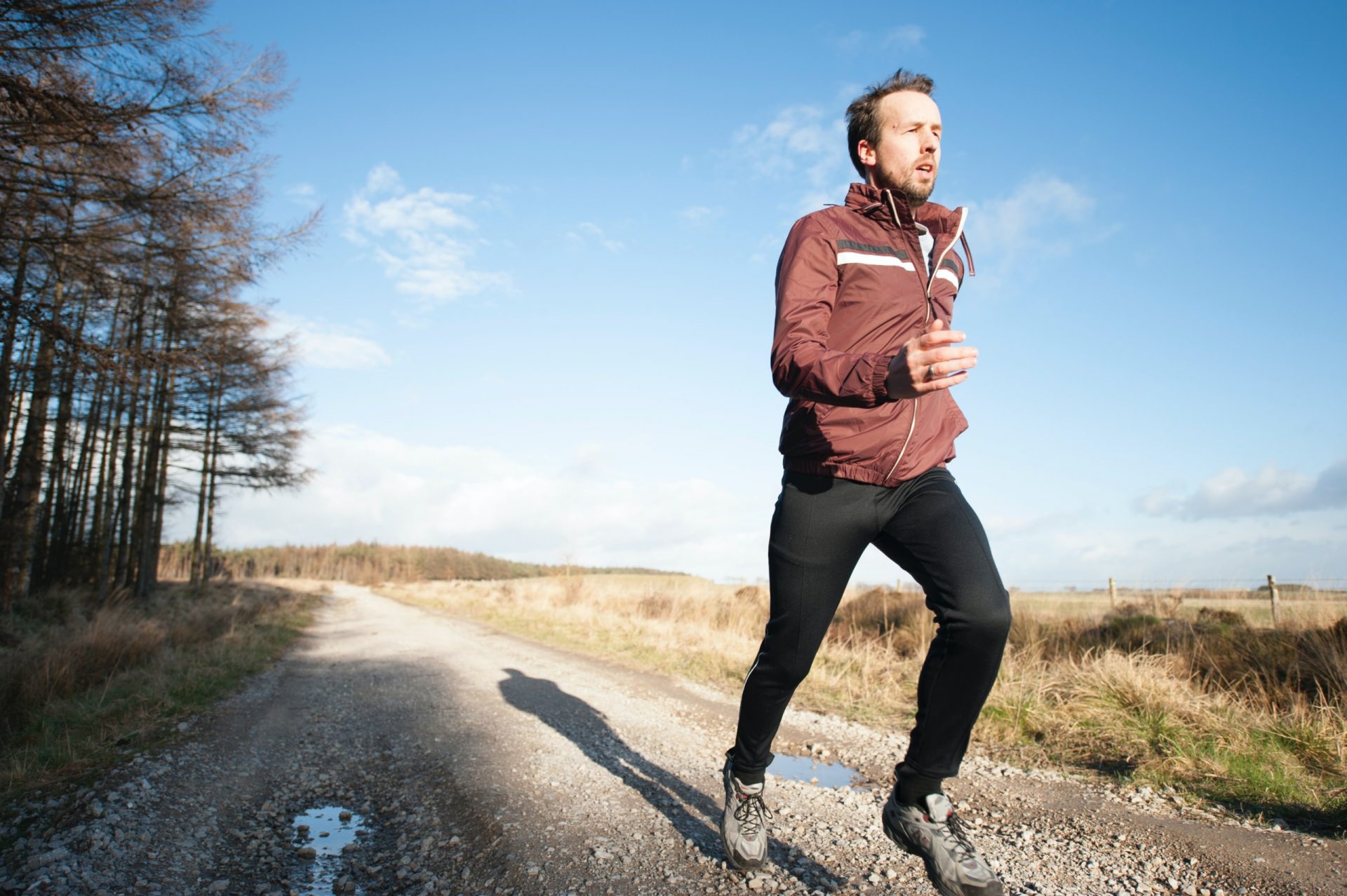 Man running on a gravel road in the country as part of his commitment to the future of his health.