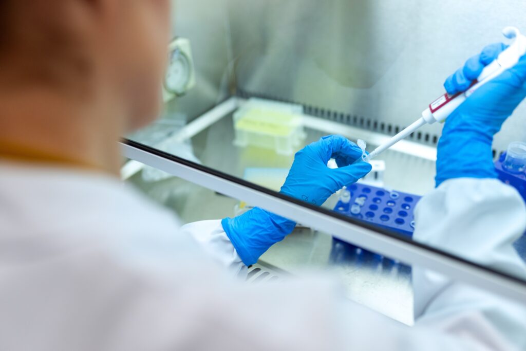 Biomedical engineer drawing a sample of blood from a test tube for an experiment.