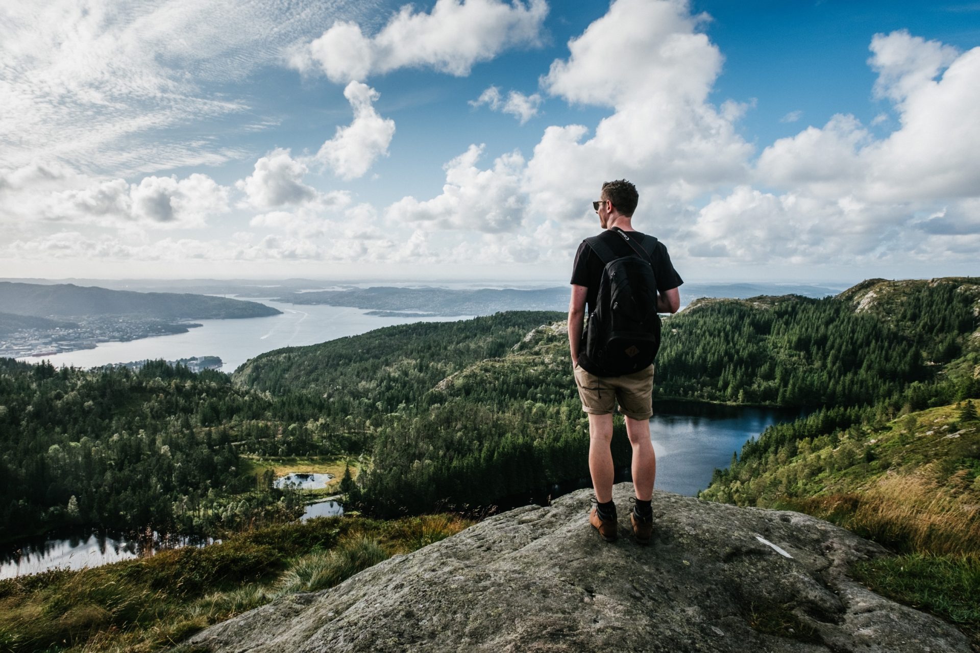 Man standing on a rock outcrop looking over a river valley.