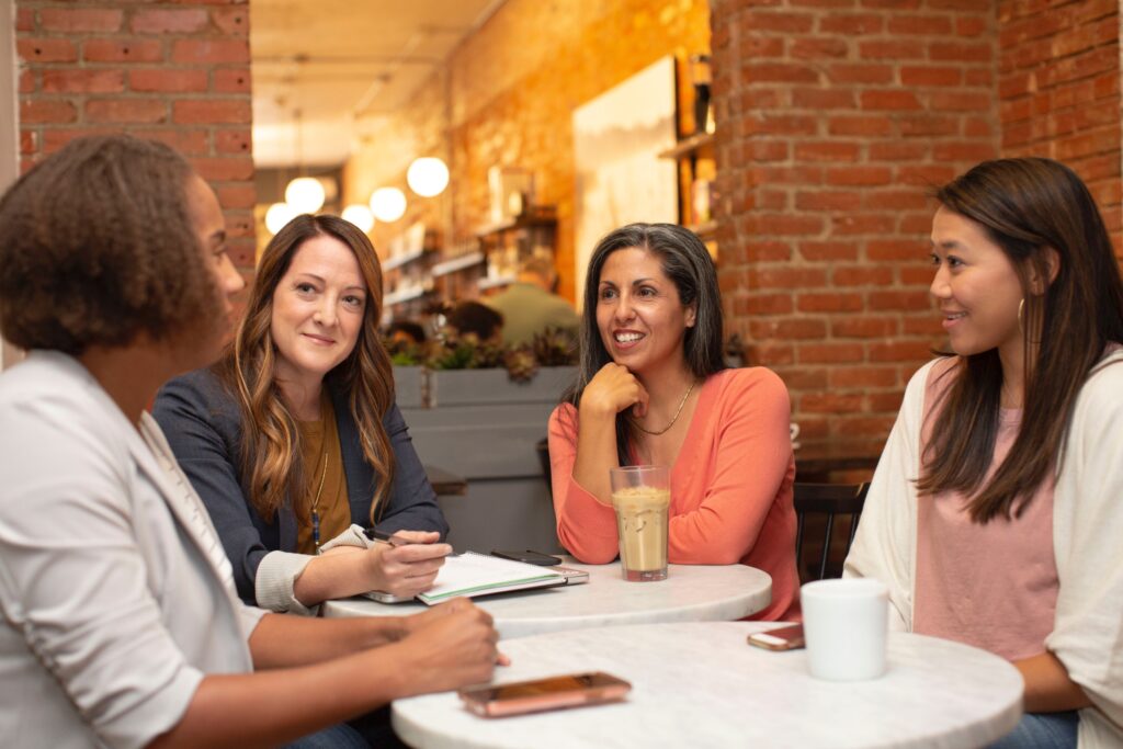 Four healthy women sitting around a table talking.