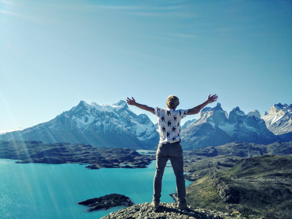 Man standing on top of a mountain with his arms outstretched.
