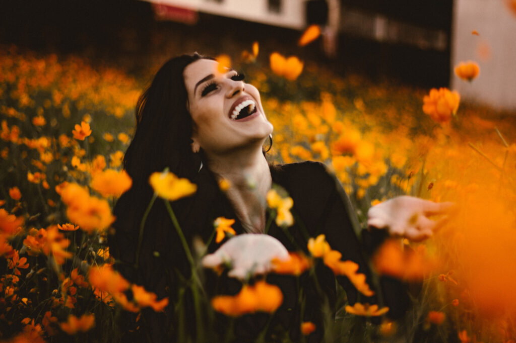 Woman sitting in a field of flowers and smiling.