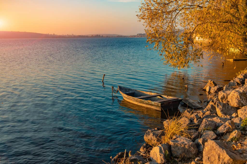 Wooden boat tied to the rocky edge of a lake.