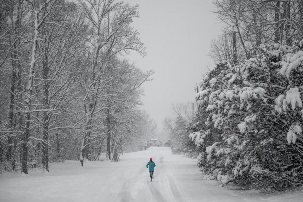 Woman jogging down a snow covered trail.