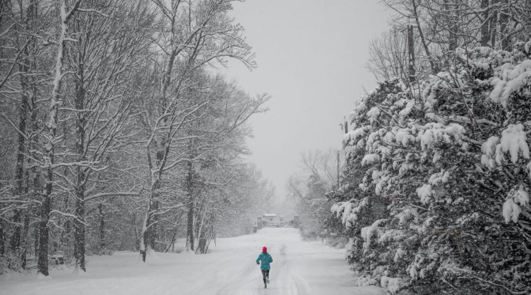 Woman jogging down a snow covered trail.