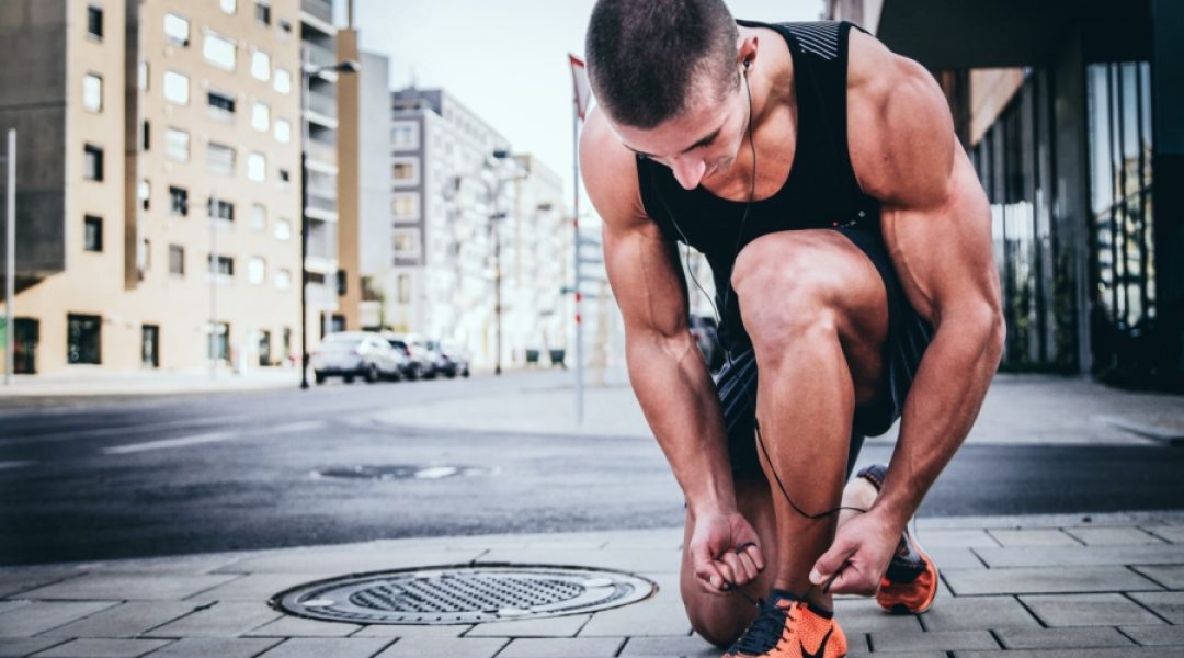 Man tying his shoe as he prepares for a run.