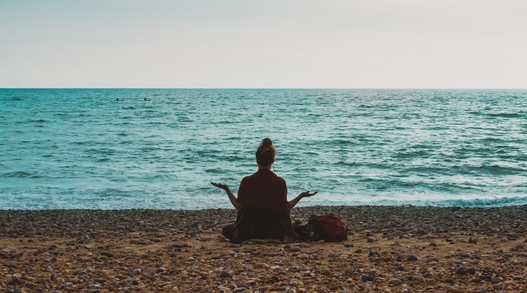 Woman meditating on the beach.