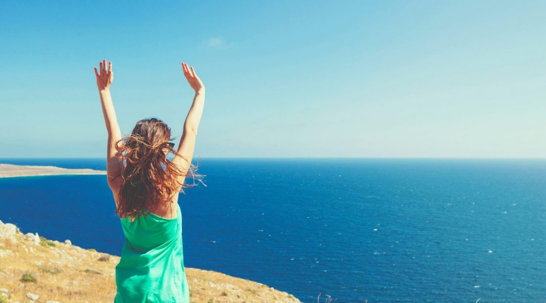 Woman standing on a cliff overlooking the ocean