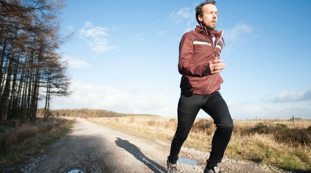 Man running on a gravel road in the country as part of his commitment to the future of his health.
