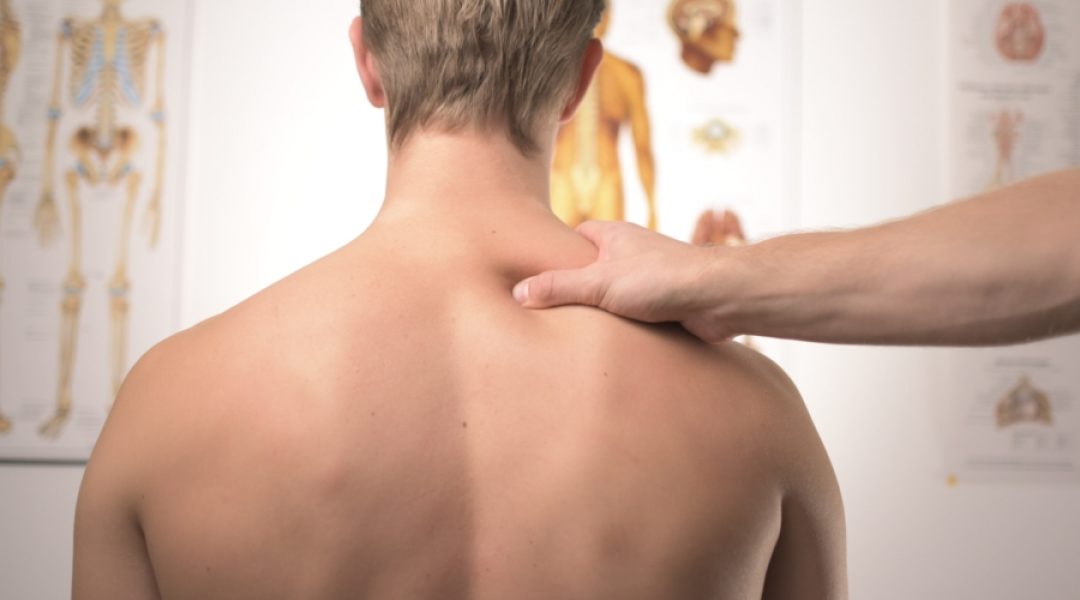 Doctor examining a man's back because he's complaining of chronic arthritis pain.