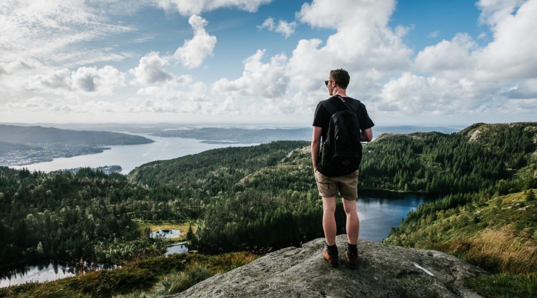 Man standing on a rock outcrop looking over a river valley.