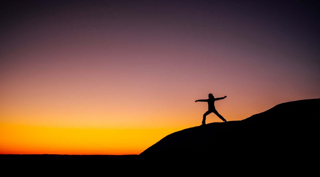 Woman doing yoga on a hill at sunset.